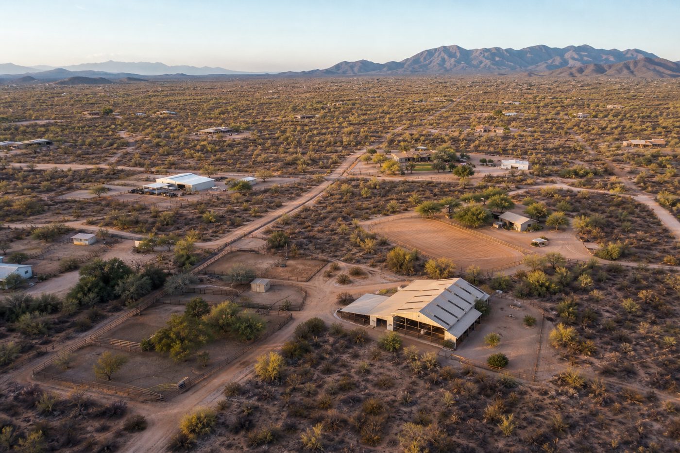 Aerial view of desert acreage parcels with barns and dirt roads